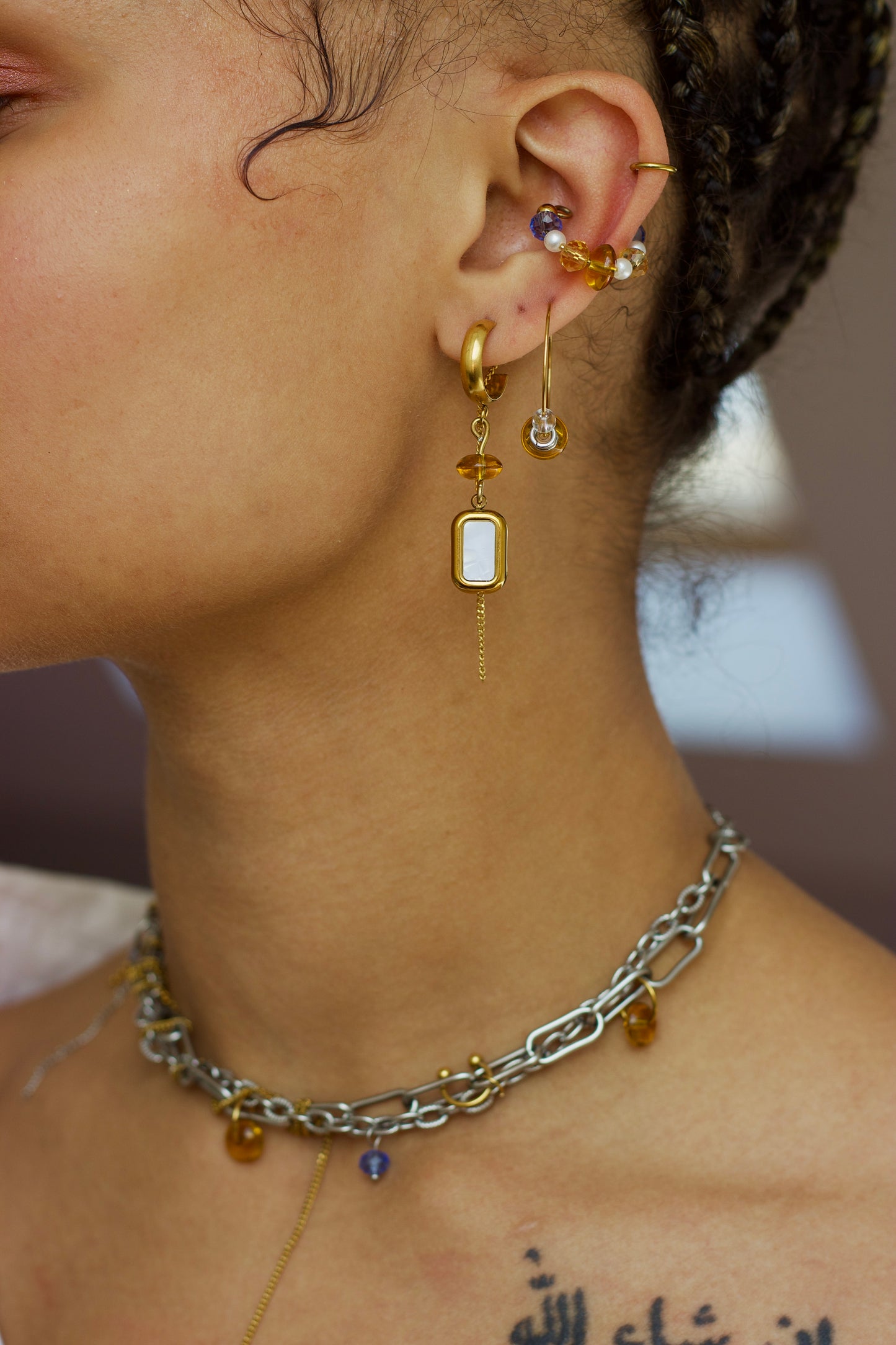 Collier choker en acier inoxydable argent et or porté avec deux monoboucles et un ear cuff assortis, vue rapprochée.