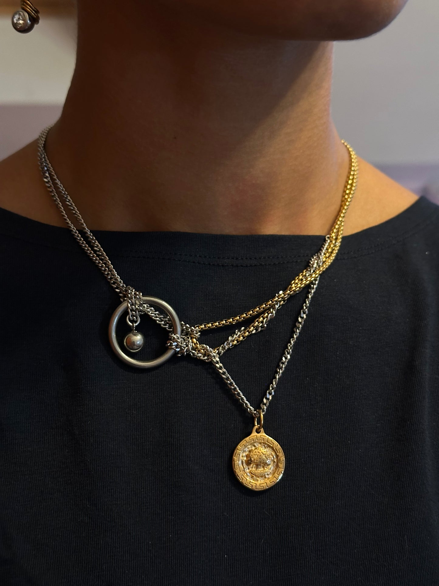 Collier en acier inoxydable argent et or avec et pendentif doré porté autour du cou, vue de face rapprochée.