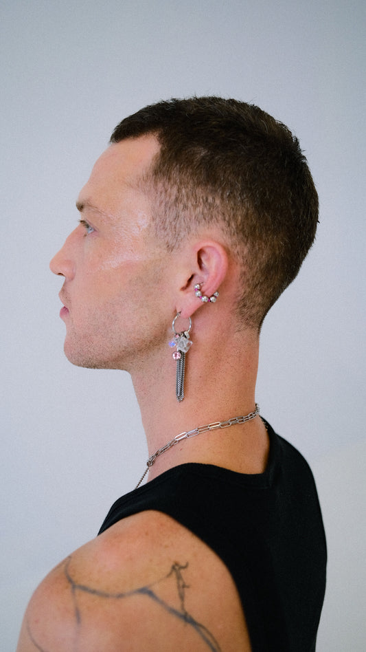 Man wearing a key-shaped earring on a plain background