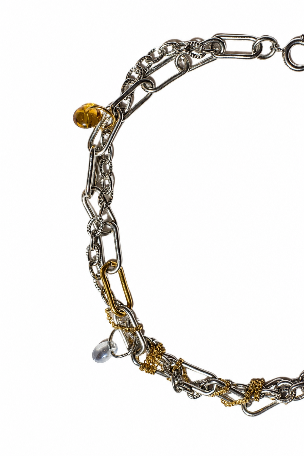 Vue rapprochée sur fond blanc d’un collier choker en acier inoxydable argent et or avec chaînes texturées, breloques translucides et détails industriels.