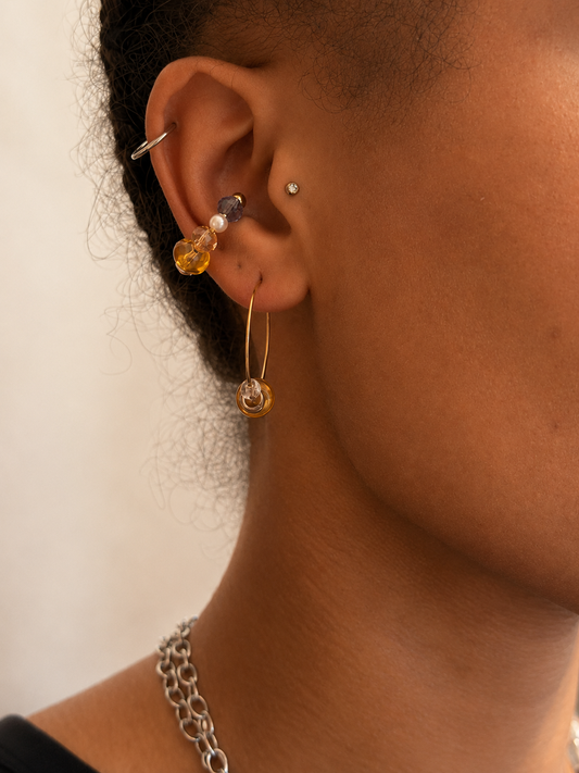 Ear cuff ajustable sans perçage en acier inoxydable plaqué PVD or avec cristaux colorés et perles nacrées, porté seul sur le cartilage de l’oreille.