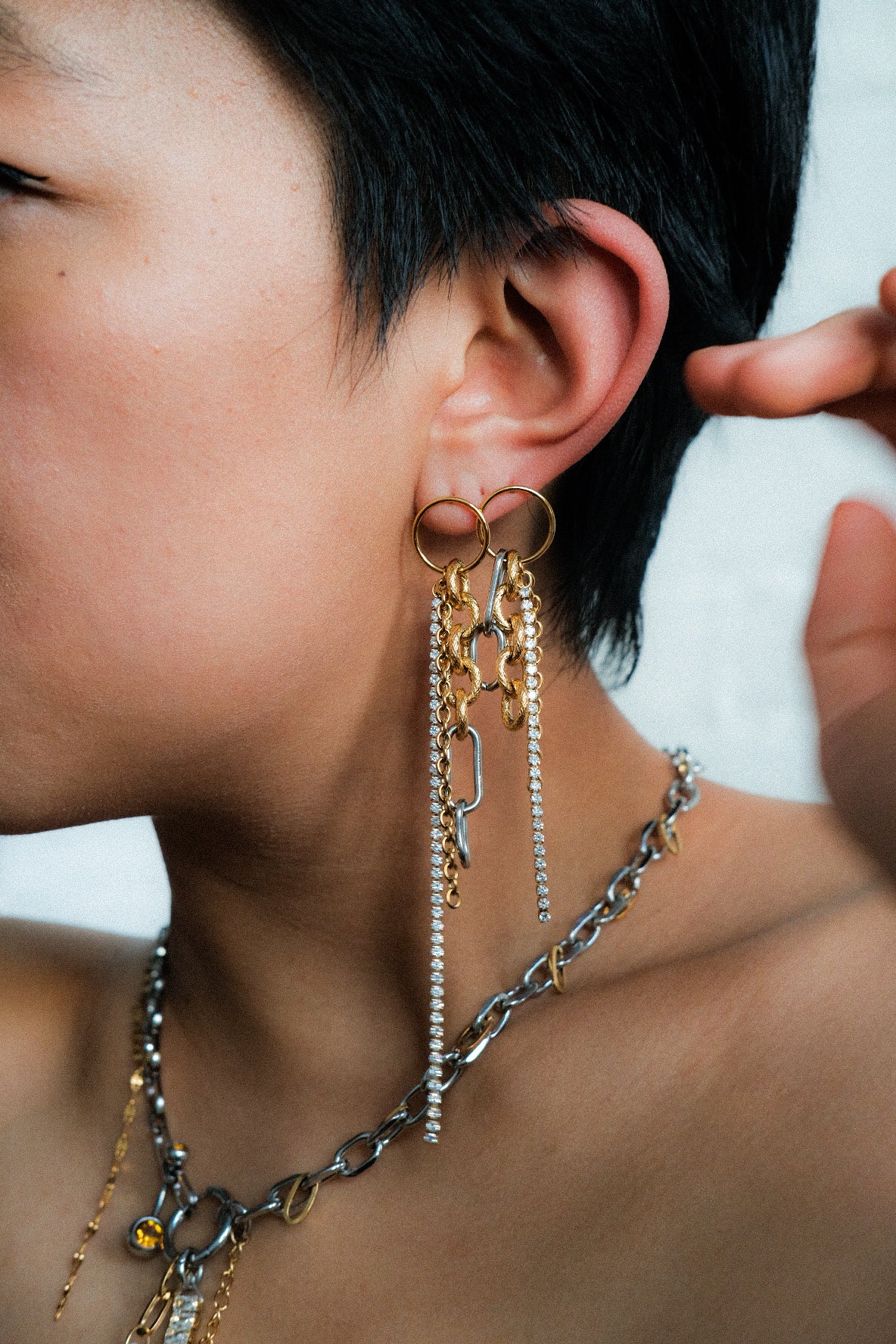 Close-up of a person wearing long, dangling earrings with a blurred background
