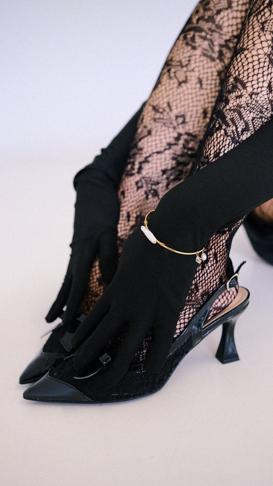 Black high-heeled shoes with fishnet stockings and black gloves on a white background