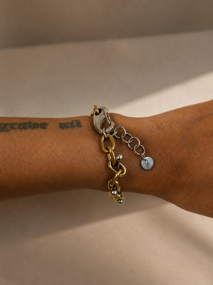 Bracelet ajustable en acier inoxydable argent et or avec piercings intégrés aux maillons, vue portée au poignet montrant l’ajustement et les proportions du bijou.