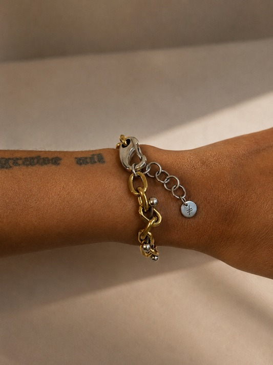 Bracelet ajustable en acier inoxydable argent et or avec piercings intégrés aux maillons, vue portée au poignet montrant l’ajustement et les proportions du bijou.