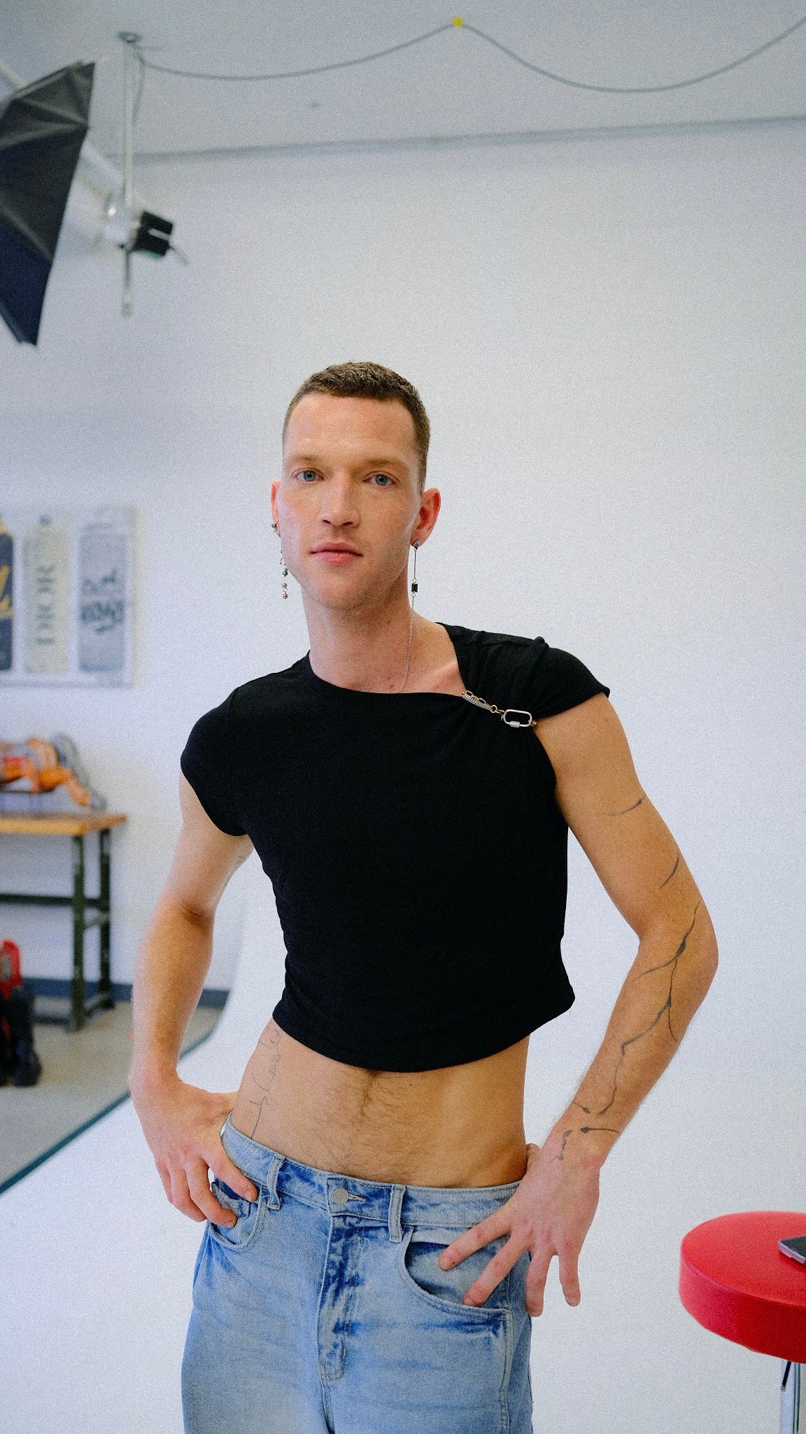 Person wearing a black crop top and blue jeans in a studio setting