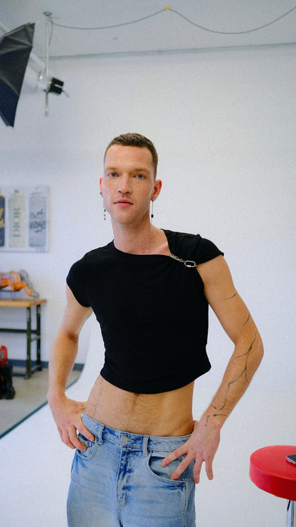 Person wearing a black crop top and blue jeans in a studio setting