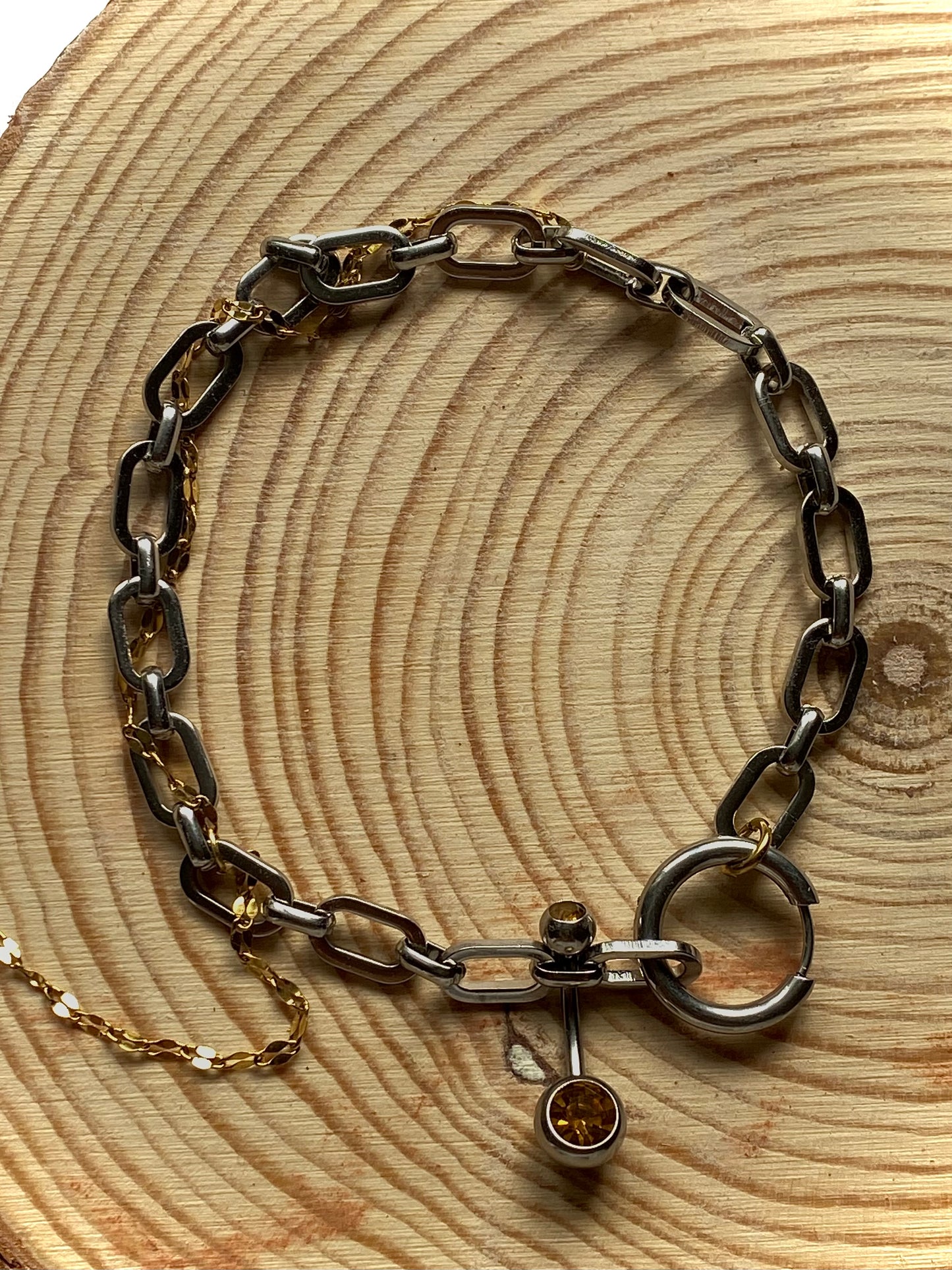 Silver chain bracelet with a clasp on a wooden surface