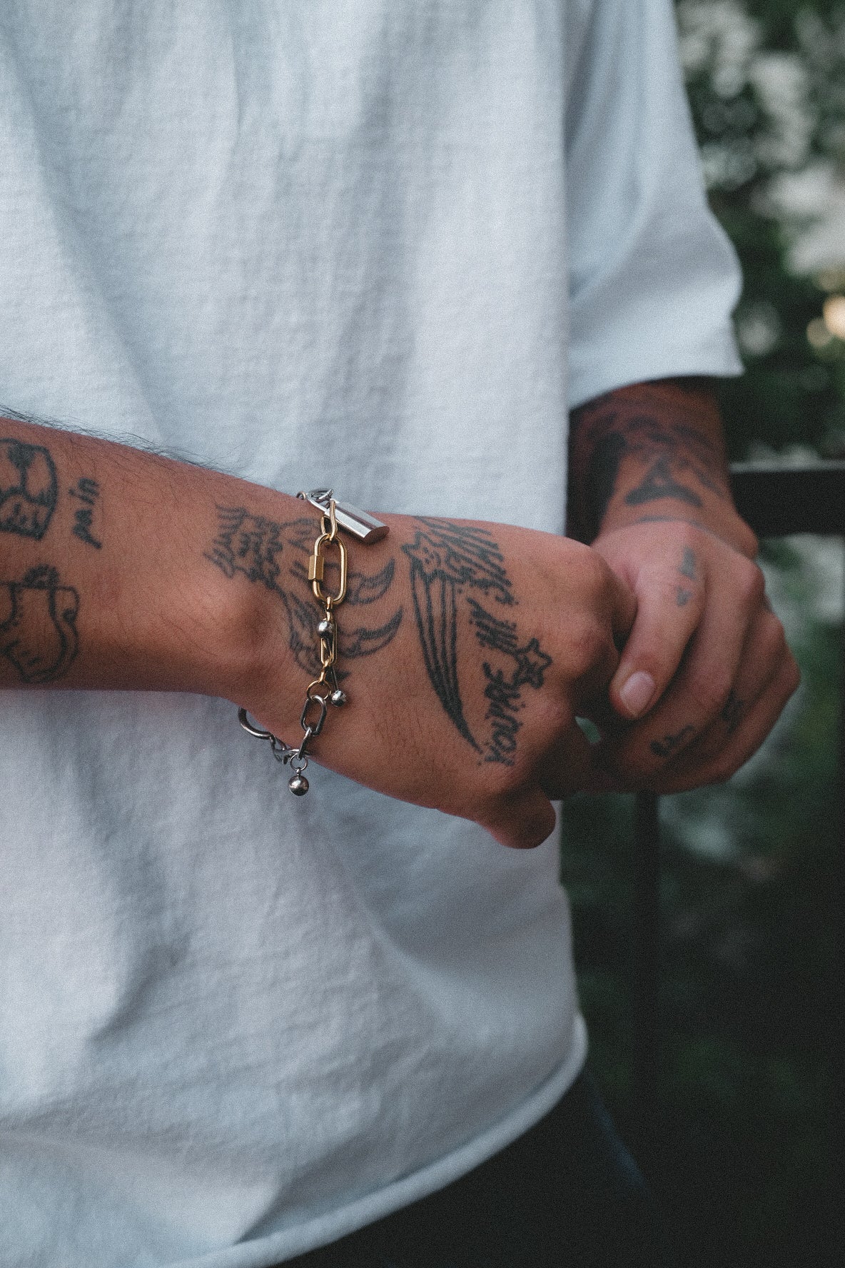 Person wearing a gold bracelet with a blurred natural background