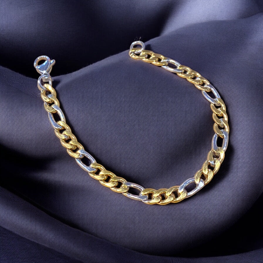 A bracelet with alternating gold and silver stainless steel links, displayed on a dark fabric background.