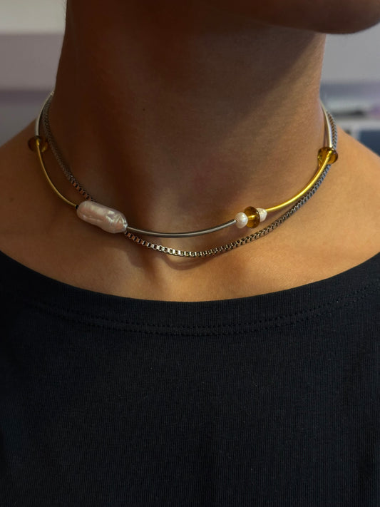 Collier choker en acier inoxydable or et argent avec perle baroque d’eau douce, porté près du cou, vue de face.