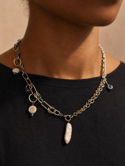 Collier modulaire en acier inoxydable argent et or avec perle naturelle amovible et accents bleus, porté autour du cou, vue de face.