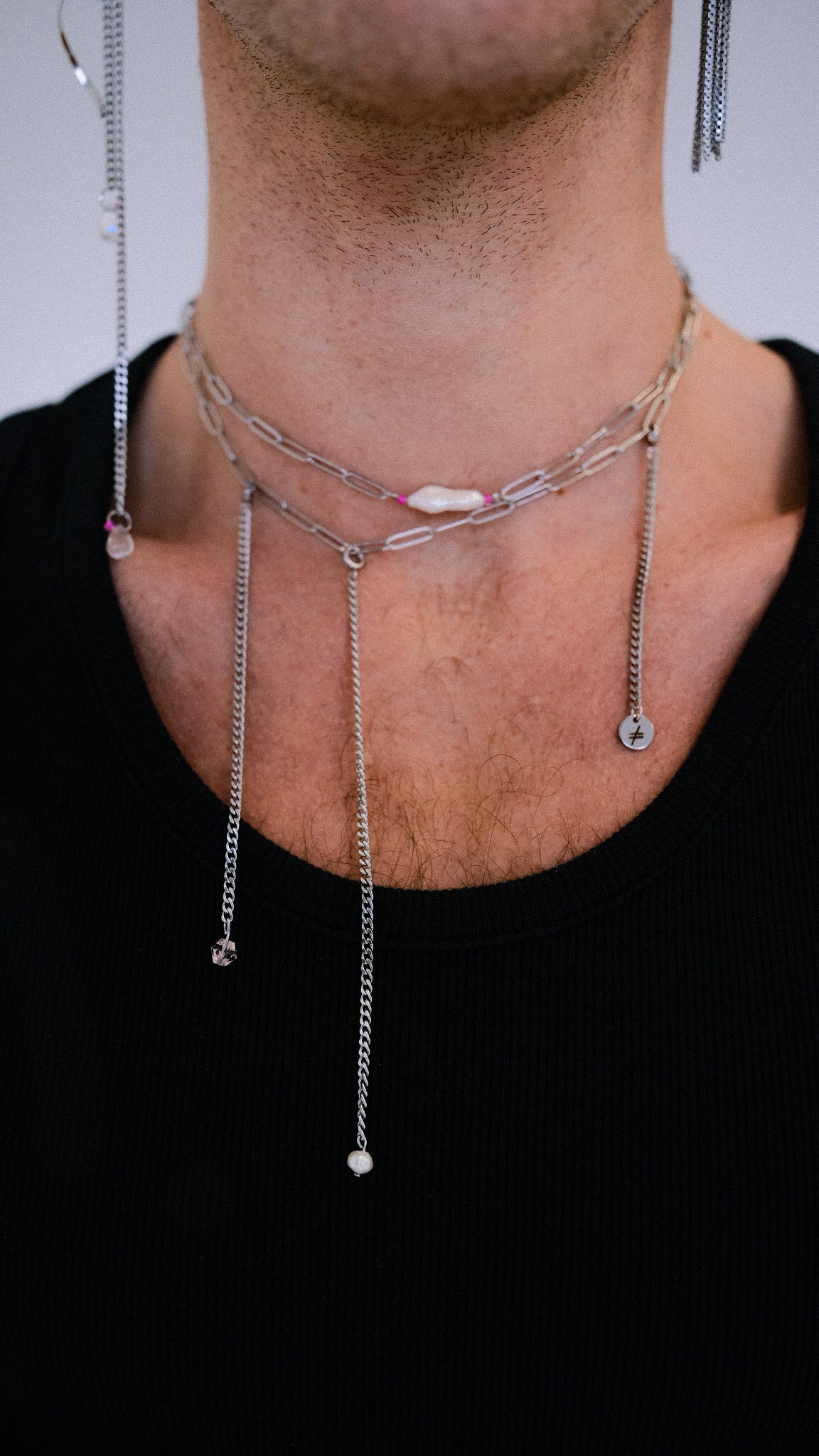 Necklace with small pendants on a person wearing a black shirt