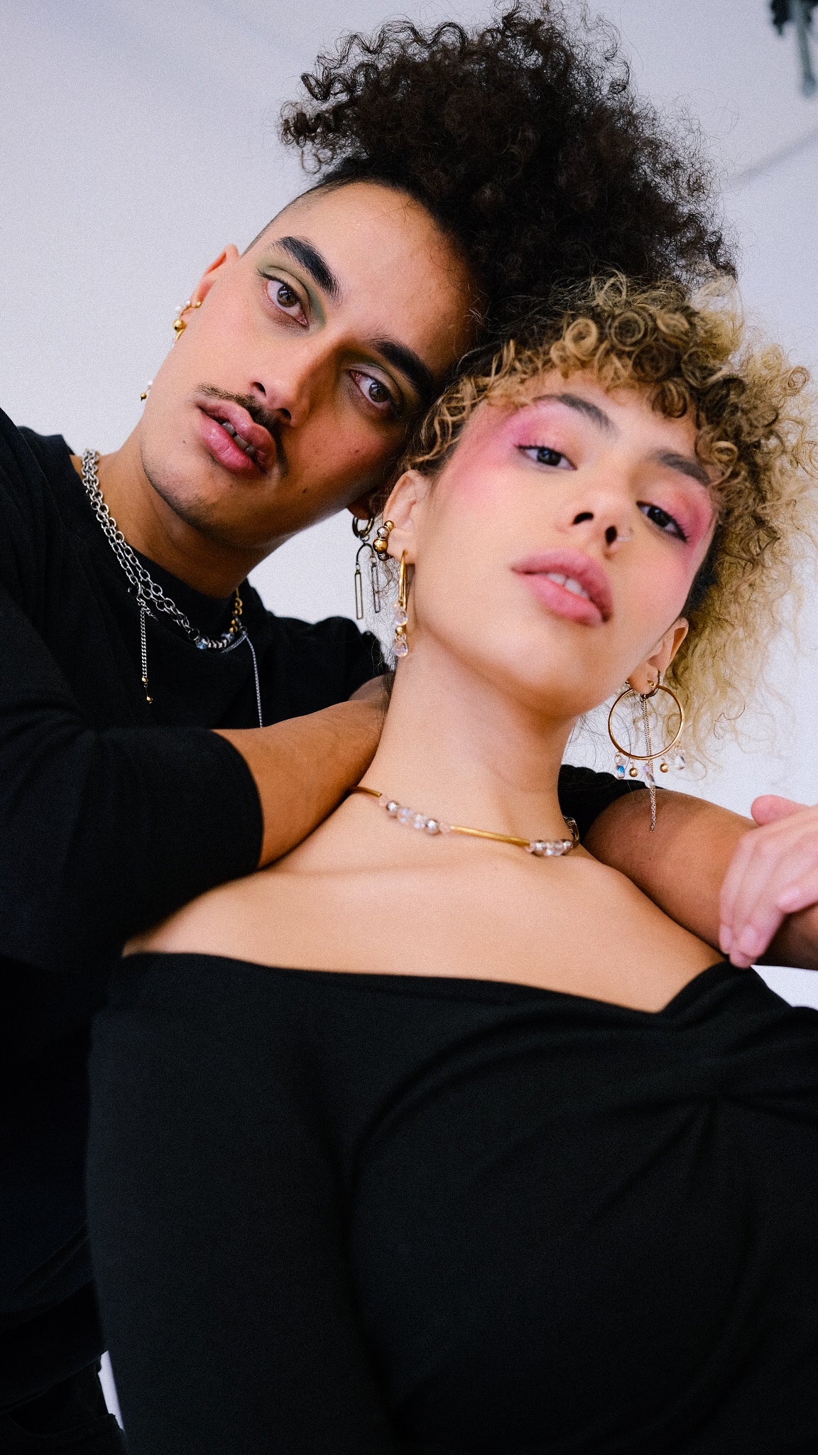 Two people posing closely together with a neutral background