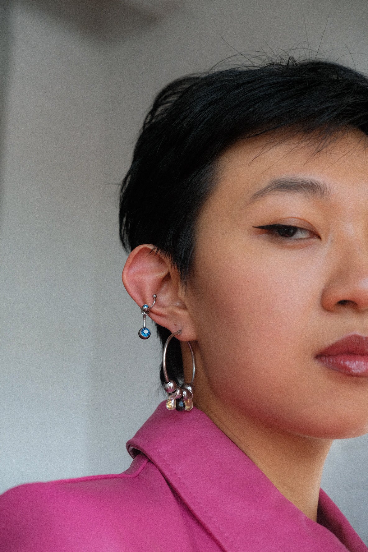 Close-up of a person wearing earrings with a neutral background