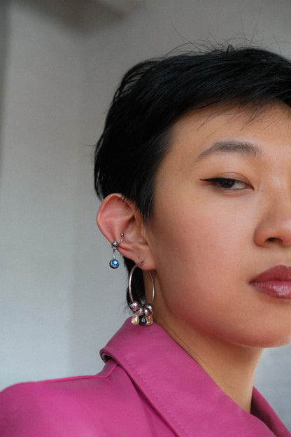 Close-up of a person wearing earrings with a neutral background