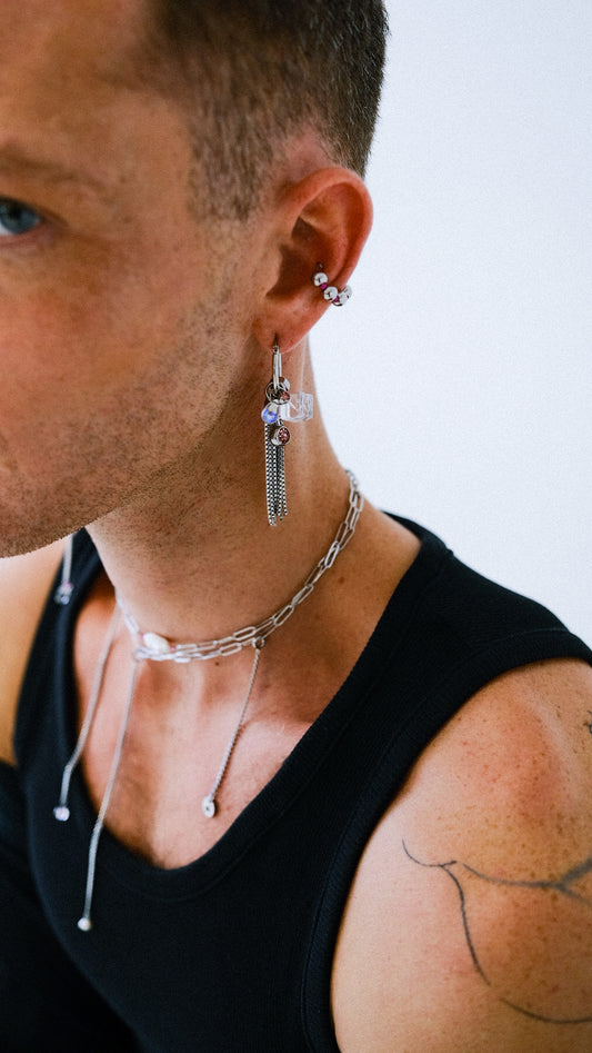 Man wearing earrings and a necklace with a blurred background