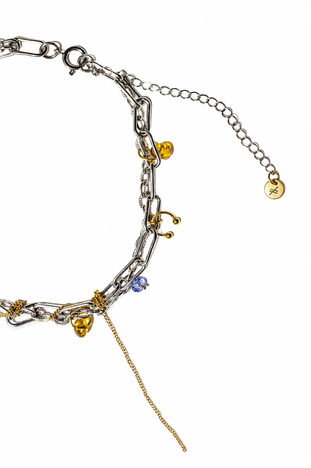 Gros plan sur un collier choker en acier inoxydable argent et or avec breloques ambrées, piercing décoratif et chaîne pendante, vue de haut sur fond blanc.