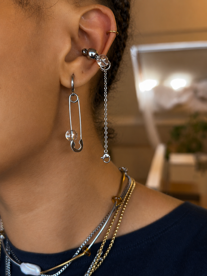 Earcuff ajustable sans perçage relié à une mono-boucle en acier inoxydable argenté avec perles translucides, porté à l’oreille, vue de profil.