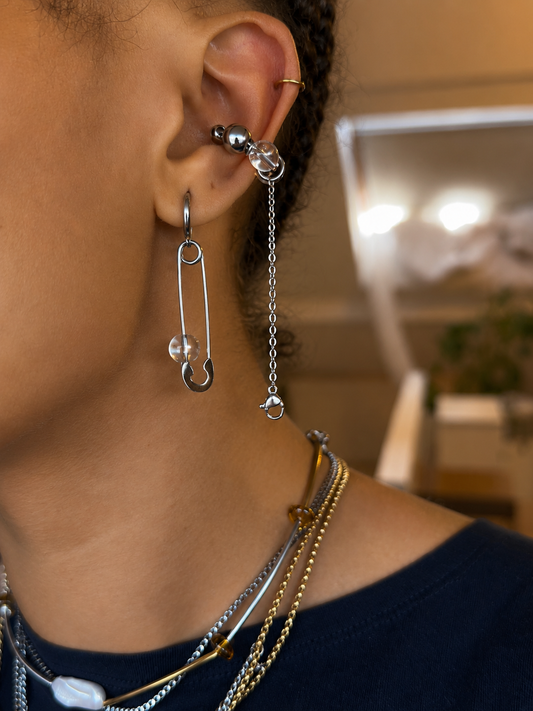 Earcuff ajustable sans perçage relié à une mono-boucle en acier inoxydable argenté avec perles translucides, porté à l’oreille, vue de profil.