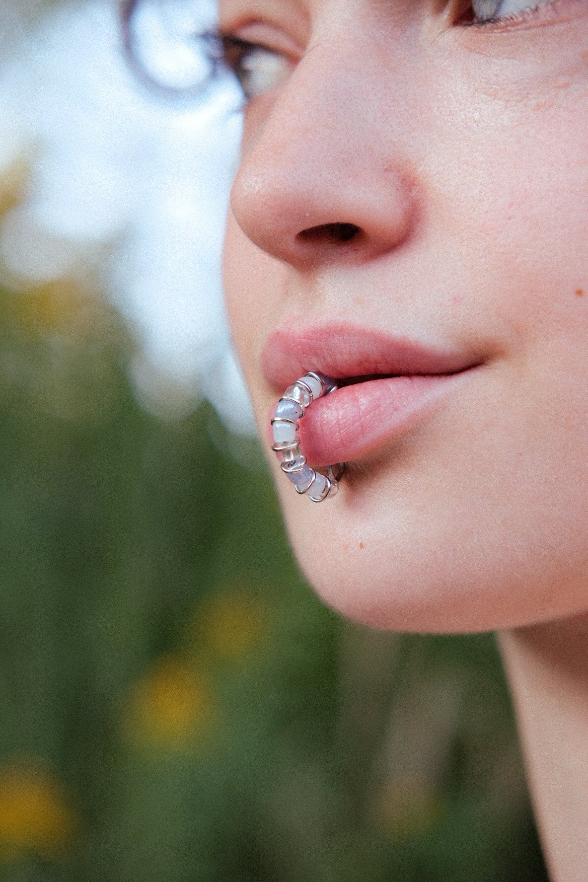 Close-up of a person wearing clear aligners with a blurred natural background